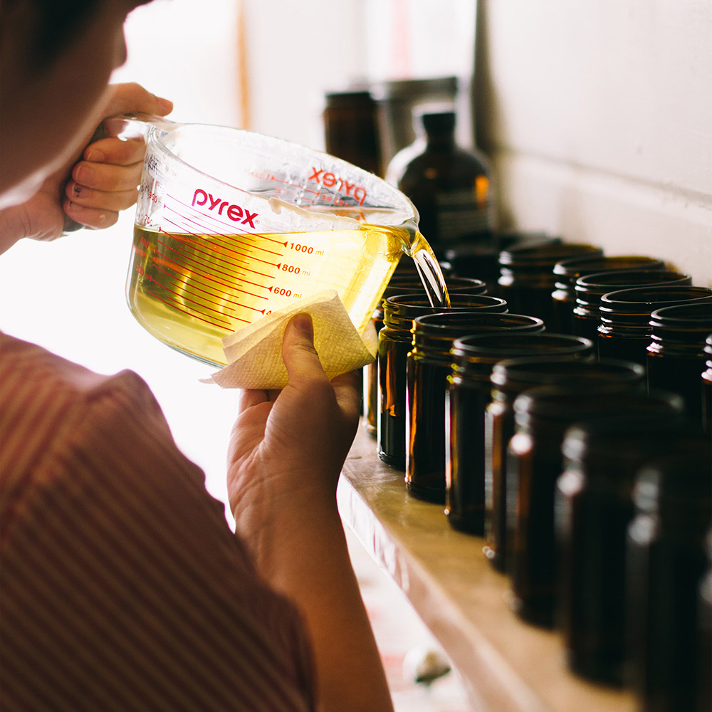 Artist pouring wax into a candle jar.