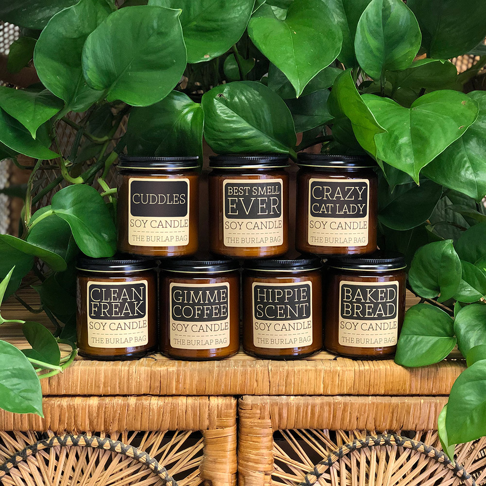 Soy candles sitting on a hutch with green plants.